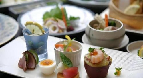 a plate of food on a table with plates of food at Hotel Myoken Tanaka Kaikan in Kirishima