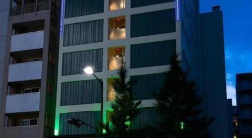 a tall building with a christmas tree in front of it at Green Hill Hotel Urban in Kobe