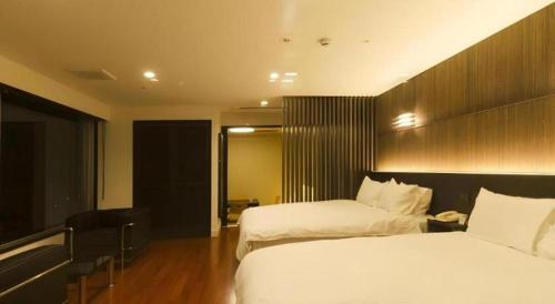 a hotel room with two beds and a desk at Kannawa Onsen Hotel Sansuikan in Beppu