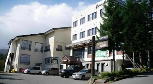 a white building with cars parked in front of it at Espoir Misawa in Hakuba