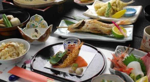 a table topped with plates of food with different foods at Minshuku Shima in Kaga