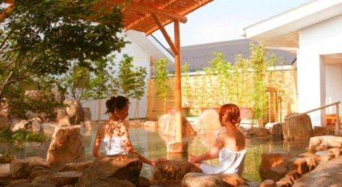 two children sitting on rocks in a pool of water at Hirata Maple Hotel in Izumo