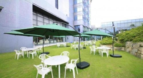 a group of tables and chairs with green umbrellas at Centurion Hotel Technoport Fukui- Artificial Radium Hot Spring in Sakai