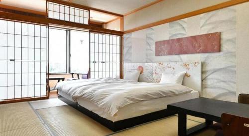 a bedroom with a bed and a table and windows at Centurion Hotel Technoport Fukui- Artificial Radium Hot Spring in Sakai