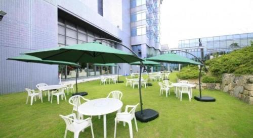 a group of tables and chairs with green umbrellas at Centurion Hotel Technoport Fukui- Artificial Radium Hot Spring in Sakai