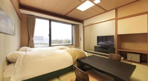 a bedroom with a bed and a table and a window at Centurion Hotel Technoport Fukui- Artificial Radium Hot Spring in Sakai
