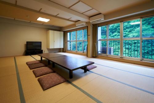 a large room with a table and some windows at Shima Onsen Yuzuriha in Nakanojo