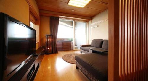 a living room with a couch and a flat screen tv at Luxury Wa Hotel Kaze No Kaori in Ito