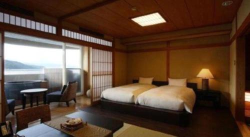 a bedroom with a bed and a living room with a window at Luxury Wa Hotel Kaze No Kaori in Ito