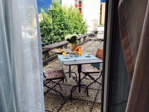a table and chairs on a balcony with a table and drinks at Bottega del Vino Guesthouse in Locarno