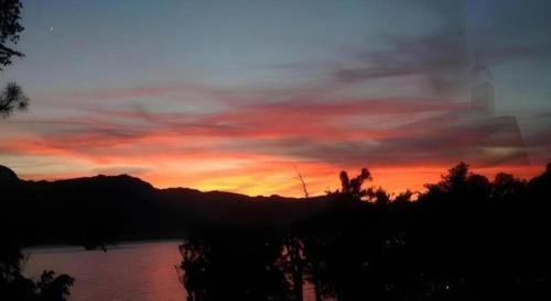 a sunset over a body of water with trees and clouds at Towadako Lakeside Hotel in Towada