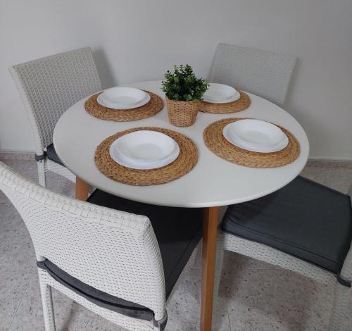 a white table with plates and a potted plant on it at Xaloc & Garbí apartamentos in Cala Galdana