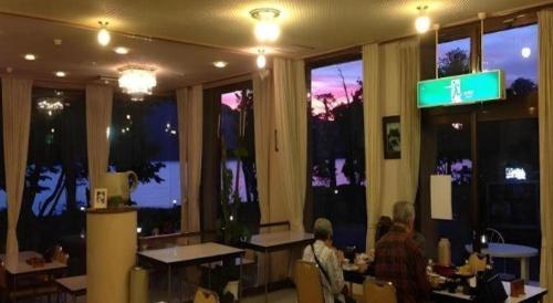 a room with people sitting at tables in a restaurant at Towadako Lakeside Hotel in Towada