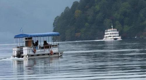 a boat on the water with a cruise ship at Towadako Lakeside Hotel in Towada