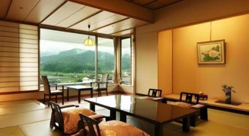 a dining room with a table and chairs and a large window at Shiratamano Yu Senkei in Shibata