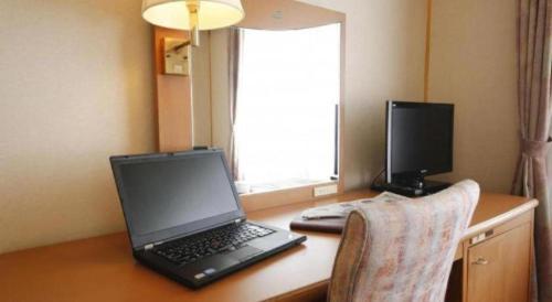 a laptop computer sitting on top of a wooden desk at Ako Park Hotel in Ako