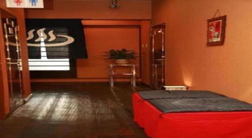 a room with a red ottoman in front of a door at Business Hotel Wako in Ichinomiya