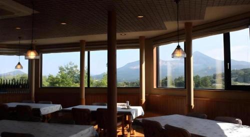 a restaurant with tables and chairs and large windows at Petit Hotel Hoshi no Shizuku in Kitashiobara