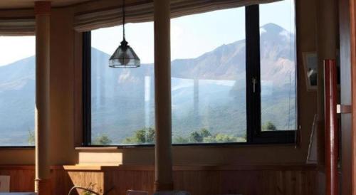 a room with a large window with a view of mountains at Petit Hotel Hoshi no Shizuku in Kitashiobara