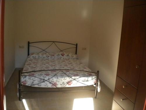 a small bedroom with a bed with a floral comforter at Marias Alikambos in Alikampos
