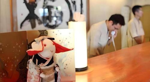 a man playing a video game in a box on a table at Tsukino Sumika Atami Juraku Hotel in Atami