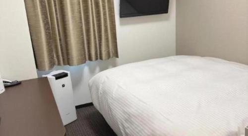 a bedroom with a white bed and a table and a window at E Hotel Kumagaya Annex in Kumagaya