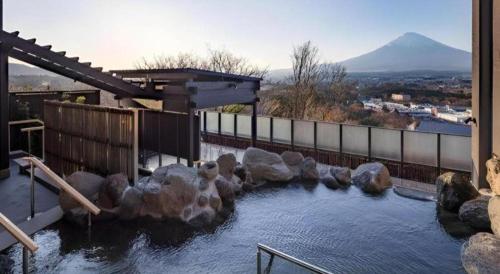a pool of water with rocks and a mountain at HOTEL CLAD in Fuji