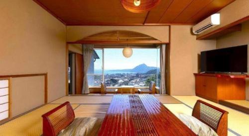 a living room with a large table and a large window at Yukemuri no sato azumaya in Beppu