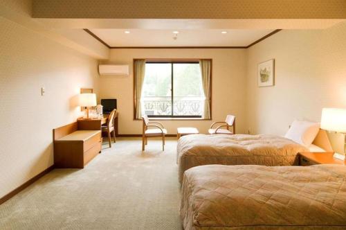 a hotel room with two beds and a desk at HOTEL WINDSOR in Nakatsugawa