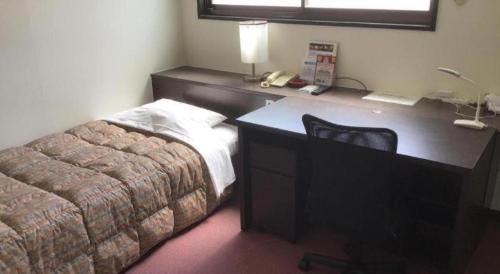 a bedroom with a desk with a bed and a telephone at HotelNewYama in Yamanouchi