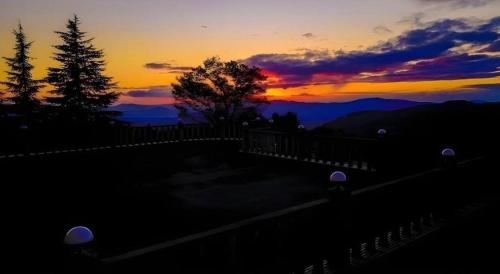 a sunset in the mountains with a fence and trees at HOTEL WINDSOR in Nakatsugawa
