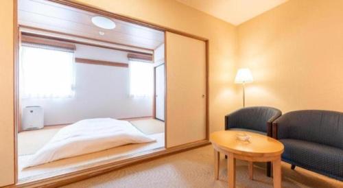 a room with a mirror and a bed and a chair at Tabist Sunshine Koga in Koga