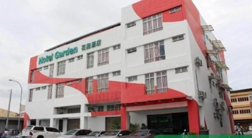 a white and red building with cars parked in a parking lot at THE GARDEN HOTEL (BANTING) SDN. BHD. in Banting