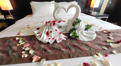 two swans dressed in white are on a bed at RH Hotel Sibu in Sibu