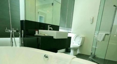 a bathroom with a tub and a toilet and a mirror at RH Hotel Sibu in Sibu