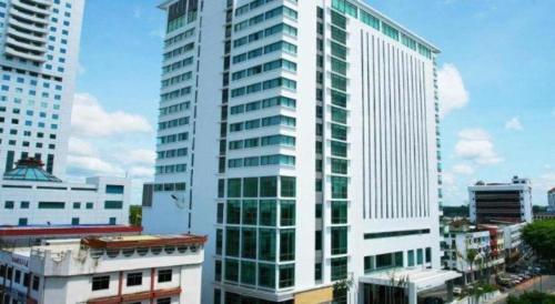 a tall white building with windows in a city at RH Hotel Sibu in Sibu