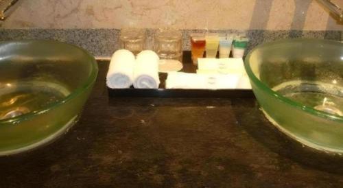 a counter top with two bowls and rolls of toilet paper at Century Helang Hotel in Pantai Cenang