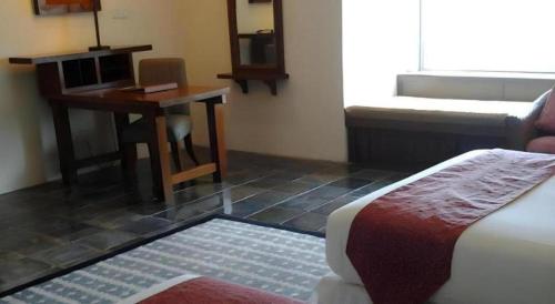 a room with a desk and a bed and a table at Century Helang Hotel in Pantai Cenang