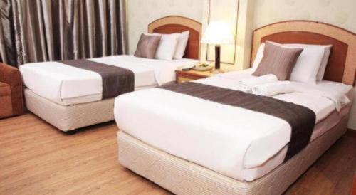 two beds sitting in a hotel room with at Pelican Hotel in Batu Pahat