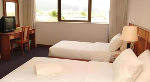 a hotel room with two beds and a desk and a television at Pelican Hotel in Batu Pahat