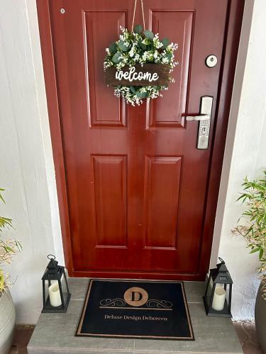 a red door with a welcome mat in front of it at Deluxe Design Apartman in Debrecen