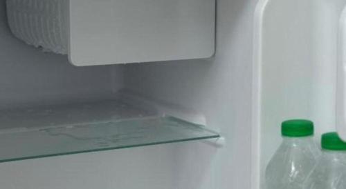 a refrigerator with a bottle of water and a green lid at Hotel Zamburger Bentong in Bentong