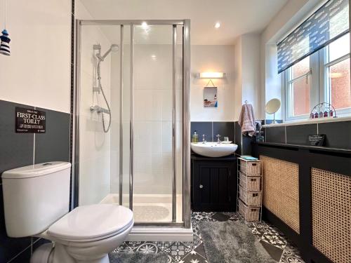 a bathroom with a shower and a toilet and a sink at Poppyline Mews in Sheringham
