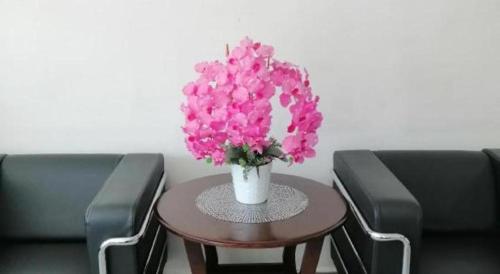 a vase with pink flowers on a table between two chairs at Hotel Darulaman Alor Setar in Alor Setar
