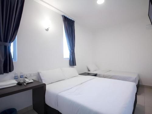 a bedroom with two beds and a desk and a window at D Nice Hotel in George Town