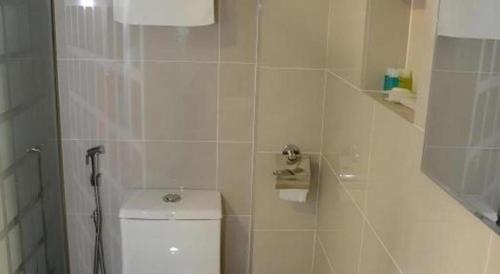a white bathroom with a toilet and a shower at Elegant Hotel in Batu Pahat