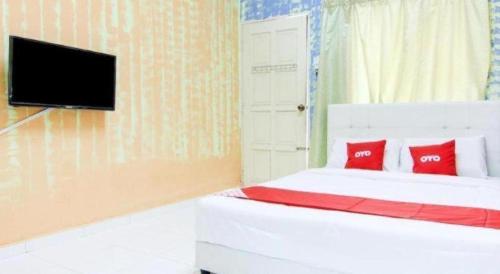 a bedroom with a bed with red pillows and a tv at OYO 89684 Mawaddah Inn Stay in Tangkak
