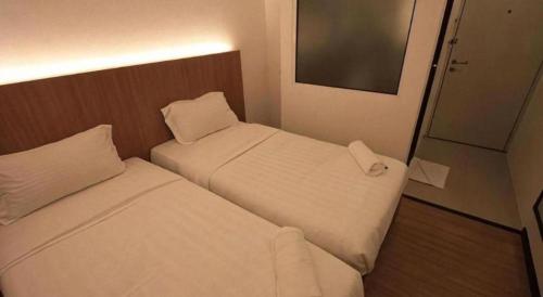 two white beds in a small room with a mirror at Place2stay @ Campus Hub in Kuching
