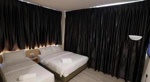a bedroom with two beds and a window with black curtains at Place2stay @ Campus Hub in Kuching