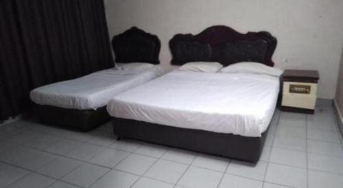 two beds in a hotel room with white floors at OYO 90376 Centre Point Hotel in Limbang